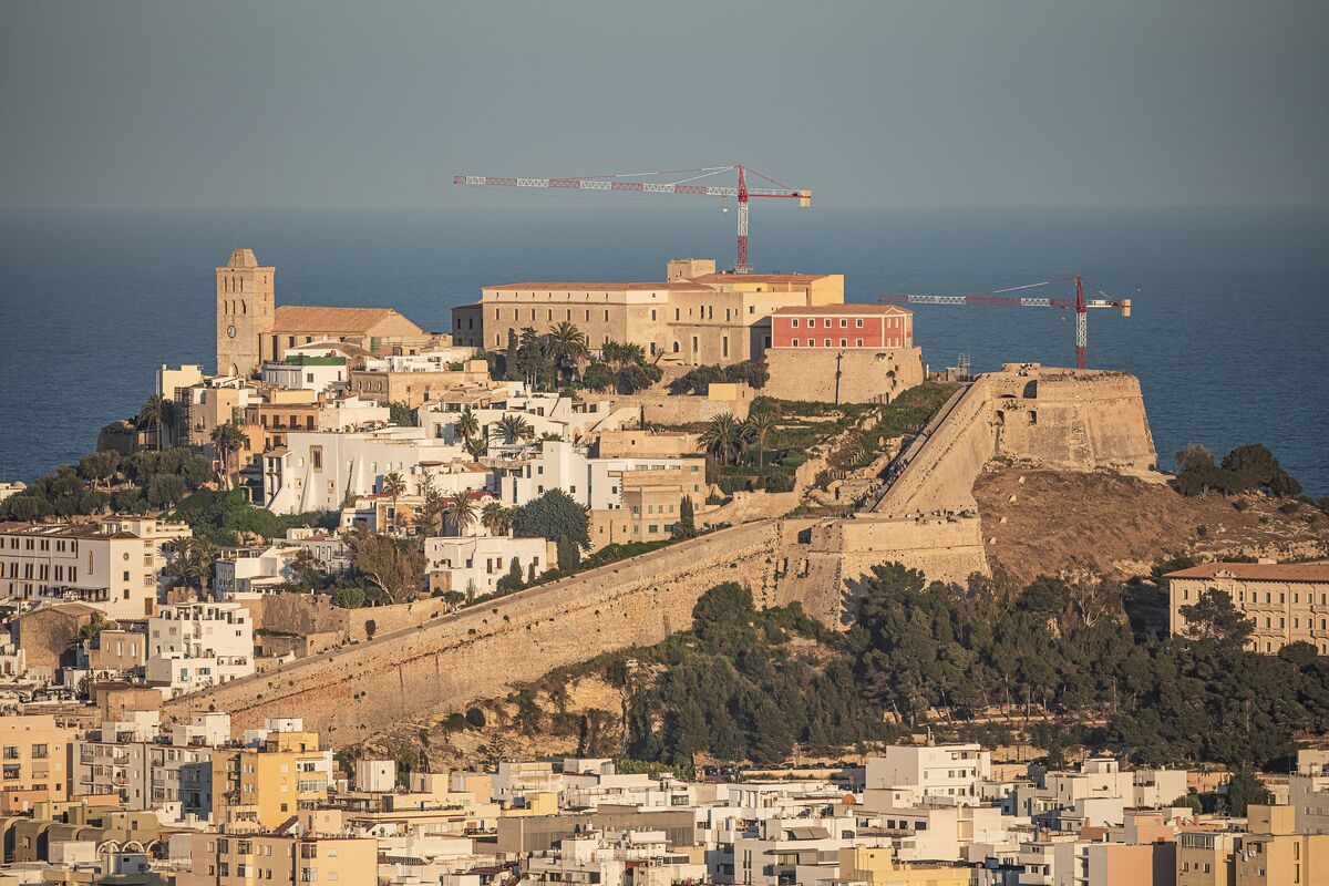 The whitewashed walls and bastions of Dalt Vila, Ibiza's old town, rising above the sea with bougainvillea in the foreground